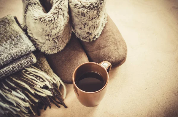 Sıcak ev kıyafetleri. Yünlü ekose kumaş, terlik ve bir fincan sıcak içecek..