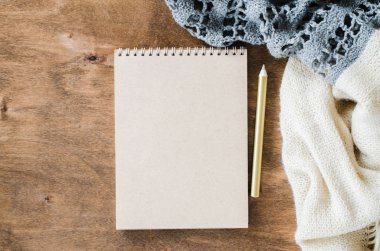 Düz örme battaniye ahşap masa var boş kahverengi defter yatırın. Sonbahar ya da kış ruh rahat. Kopya alanı.