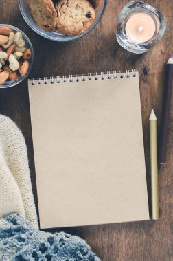 Düz örme battaniye ve ahşap masa snacks boş kahverengi defter yatırın. Sonbahar ya da kış ruh rahat. Kopya alanı.