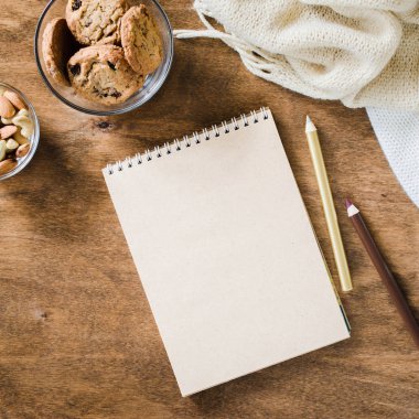 Düz örme battaniye ve ahşap masa snacks boş kahverengi defter yatırın. Sonbahar ya da kış ruh rahat. Kopya alanı.