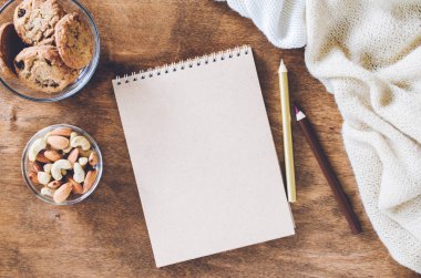 Düz örme battaniye ve ahşap masa snacks boş kahverengi defter yatırın. Sonbahar ya da kış ruh rahat. Kopya alanı.