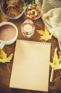 Boş kahverengi defter ile örgü battaniye, bir fincan sıcak çikolata ve ahşap masa snacks. Şükran günü kavramı. Sonbahar natürmort. Rahat sonbahar ruh hali. Kopya alanı.