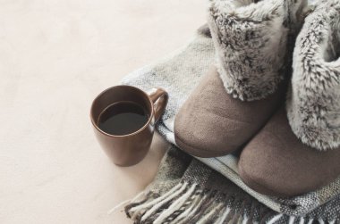Sıcak ev kıyafetleri. Yünlü ekose kumaş, terlik ve bir fincan sıcak içecek..