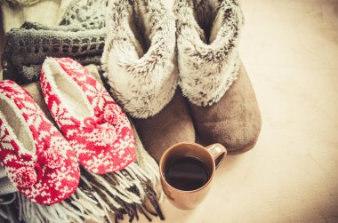 Sıcak ev kıyafetleri. Yünlü ekose kumaş, terlik ve bir fincan sıcak içecek..