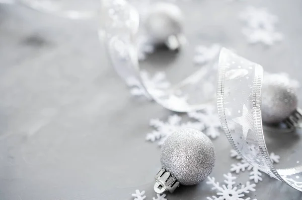 Silver Christmas background. Curly ribbon with decorative balls and snowflakes. Xmas decorations. Copy space.