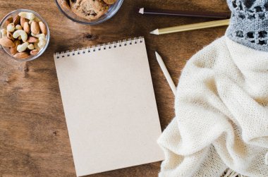 Düz örme battaniye ve ahşap masa snacks boş kahverengi defter yatırın. Sonbahar ya da kış ruh rahat. Kopya alanı.