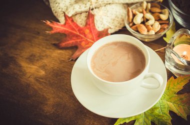 Bir fincan sıcak kakao, fındık, kurabiye, mum ve ahşap bir masada örülmüş ekose. Sıcak sonbahar havası, ılık sonbahar.