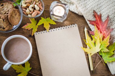 Boş kahverengi defter ile örgü battaniye, bir fincan sıcak çikolata ve ahşap masa snacks. Şükran günü kavramı. Sonbahar natürmort. Rahat sonbahar ruh hali. Kopya alanı.