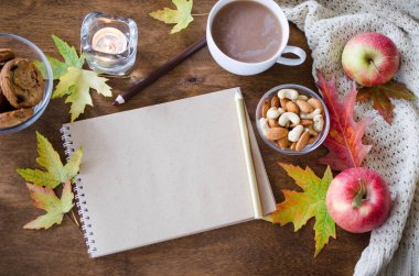 Boş kahverengi defter ile örgü battaniye, bir fincan sıcak çikolata ve ahşap masa snacks. Şükran günü kavramı. Sonbahar natürmort. Rahat sonbahar ruh hali. Kopya alanı.