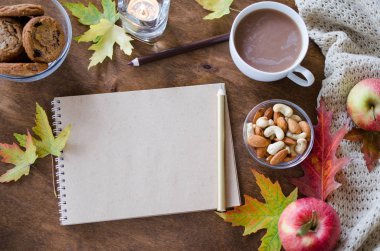 Boş kahverengi defter ile örgü battaniye, bir fincan sıcak çikolata ve ahşap masa snacks. Şükran günü kavramı. Sonbahar natürmort. Rahat sonbahar ruh hali. Kopya alanı.