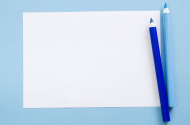 İki mavi kalem ve Kağıt beyaz boş sayfa. Mock-up kopya alanı. Yukarıdan görünüm, eğitim kavramı.