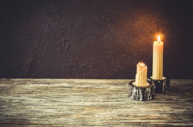 Eski bir ahşap masa üzerinde yanan mum. Mistik koyu arka plan.