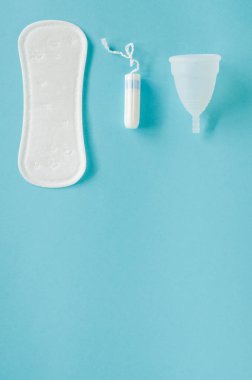 Kadın hijyen ürünleri - adet Kupası, hijyenik ped ve tampon mavi bir arka plan üzerinde farklı türleri. Seçici odak