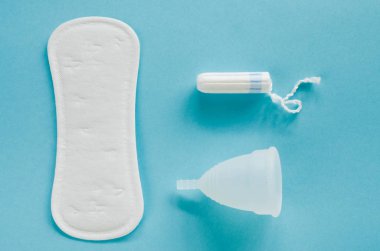 Kadın hijyen ürünleri - adet Kupası, hijyenik ped ve tampon mavi bir arka plan üzerinde farklı türleri. Seçici odak
