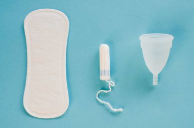 Kadın hijyen ürünleri - adet Kupası, hijyenik ped ve tampon mavi bir arka plan üzerinde farklı türleri. Seçici odak