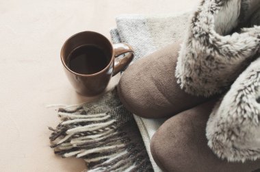 Sıcak ev kıyafetleri. Yünlü ekose kumaş, terlik ve bir fincan sıcak içecek..