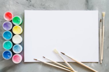 Boş beyaz kağıt sayfası, fırçalar ve boya. Çizim için alay. Yukarıdan görüntüleyin. Kopya alanı