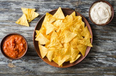 Cips mısır cipsi baharatlı domates ve peynir soslar. Meksika yemeği kavramı. Sarı Mısır salsa sosu totopos patatesler. Üstten görünüm.