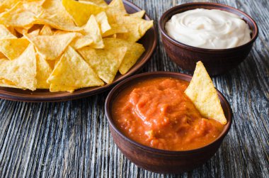 Cips mısır cipsi baharatlı domates ve peynir soslar. Meksika yemeği kavramı. Sarı Mısır salsa sosu totopos patatesler. Üstten görünüm.