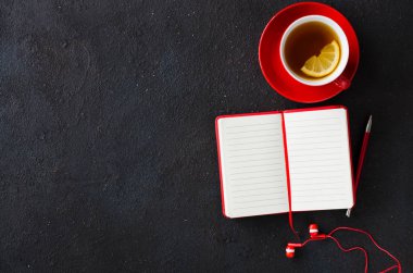 Boş kırmızı defter, bilgisayar laptop, kulaklıklar ve çay fincan. İş veya eğitim konsepti.