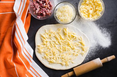 Hamur, fırın un, pizza dolum ve siyah bir tahta üzerinde haddeleme pin haddelenmiş.