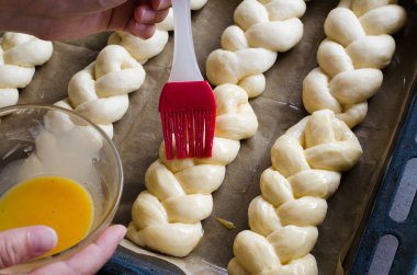 Hazırlık süreci - çiğ unbaked çörekler. Dişi el pişirmeden önce bir yumurta ile çiğ çörekler yağlar.
