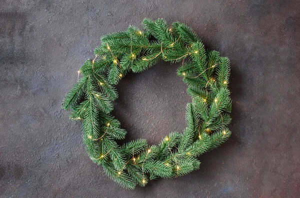 Koyu arka planda xmas ışıkları ile ağaç köknar dalları yapılmış Noel kapı çelenk.