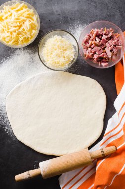 Hamur, fırın un, pizza dolum ve siyah bir tahta üzerinde haddeleme pin haddelenmiş.