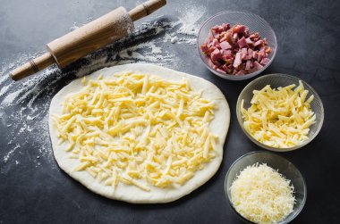 Hamur, fırın un, pizza dolum ve siyah bir tahta üzerinde haddeleme pin haddelenmiş.