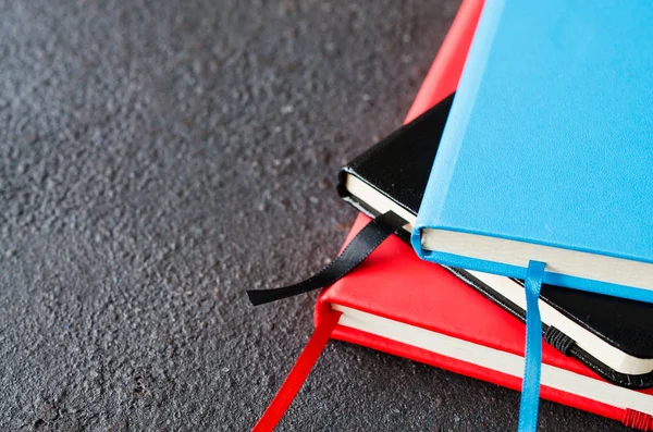 Koyu arka planda yazma veya kitap için renkli notebooklar yığını