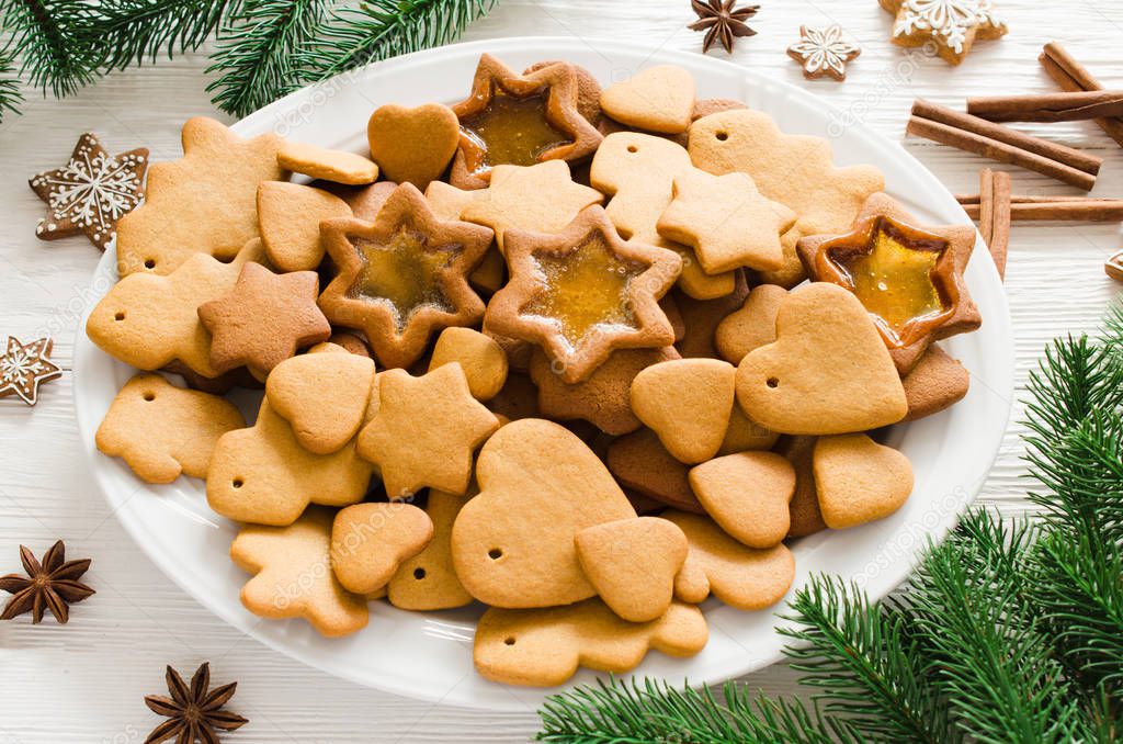 Plate full of freshly baked Christmas gingerbread on white wooden background.