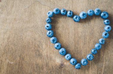 Ahşap arka plan üzerinde kalp şeklinde Taze organik yaban mersini.