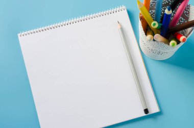 Boş defter ve mavi arka planda renkli kalemler. Kağıt arkaplan. Model Yukarı. Yukarıdan görüntüle