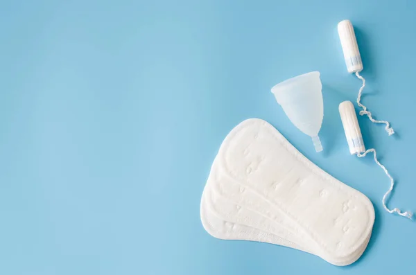 Sanitary pad, menstrual cup and tampons on blue background. Concept of feminine hygiene during menstruation. — Stock Photo, Image