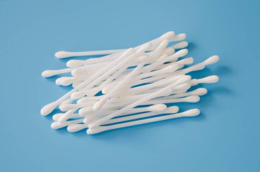 Mavi arka planda kozmetik pamuk tomurcukları. Kulakları temizlemek için çubuklar.