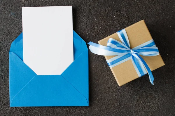 Blue envelope with blank white paper and present or gift box. Greeting card for Fathers or Grandfathers Day. — Stock Photo, Image