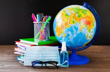 Karantina sırasında okula dönmek. Eğitim konsepti. Okul malzemeleri, tıbbi maske ve dezenfektan..