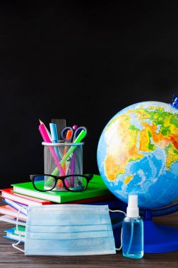 Karantina sırasında okula dönmek. Eğitim konsepti. Okul malzemeleri, tıbbi maske ve dezenfektan..