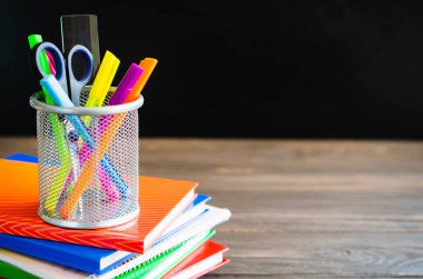 Okula dönelim. Kara tahta üzerine kitap ve okul malzemeleri yığını. Eğitim konsepti. Boşluğu kopyala