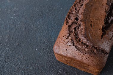 Koyu arka planda taze pişmiş ev yapımı çikolatalı ekmek ya da kek, köy tarzı. Seçici odak, metin için alan.