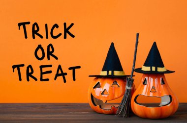 Balkabağı, süpürge ve tahta masanın üstünde cadı şapkası olan Cadılar Bayramı arkaplanı. Yazıt Cadılar Bayramı 'nda şaka mı şeker mi?.