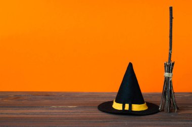 Cadılar Bayramı 'nda cadı aksesuarlarıyla iyi bayramlar: tahta masadaki şapka ve süpürge. Cadılar Bayramı kutlaması.