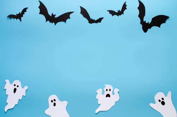 Happy Halloween holiday background with craft paper in the form of ghosts and bats on blue. Halloween holiday celebration with decoration.