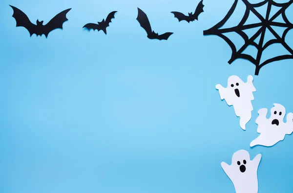 Happy Halloween holiday background with craft paper in the form of ghosts, cobwebs and bats.