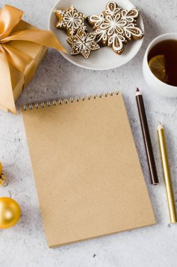 Hediye kutusu, çay ve zencefilli kurabiyeli düz kahverengi defter. Noel tebrik kartı ya da Noel Baba 'ya mektup için hazırlan. Noel dilek listesi veya yapılacaklar listesi. Sıcak kış havası. Boşluğu kopyala.