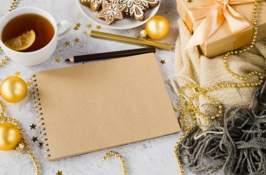 Boş kahverengi defter, hediye kutusu, çay, zencefilli kurabiye ve ekoseli Noel kompozisyonu. Noel tebrik kartı ya da Noel Baba 'ya mektup için hazırlan. Sıcak kış havası. Boşluğu kopyala.