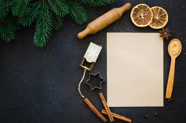 Christmas culinary background for menu or recipe. Blank paper with spice and fir branches on concrete. Top view or flat lay. Copy Space.