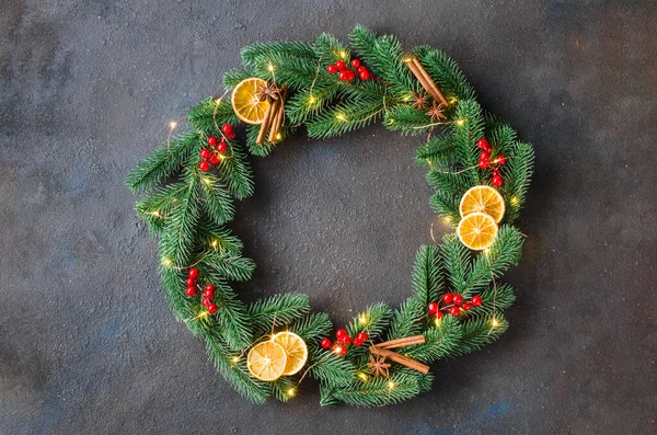 Noel çelengi, köknar dallarından yapılmıştır. Koyu arkaplanda xmas ışıkları ve süslemeleri vardır. Orta çerçevedeki boşluğu kopyala ve metin için boşalt.