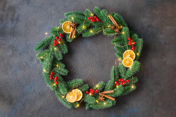 Рождественский венок из елки ель ветвей с рождественскими огнями и украшения на темном фоне. Копирование пространства в центре рамки и пустой макет для текста.