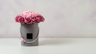 Açık renkli bir şapka kutusunda dekore edilmiş pembe ve beyaz gül buketi.